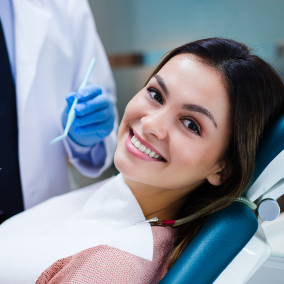 Patient holding up a dental shade guide guide to her teeth